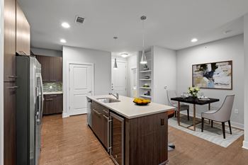A modern kitchen with a wooden island and a dining table set for two. at 46 Penn Apartment Homes, Kansas City, 64111